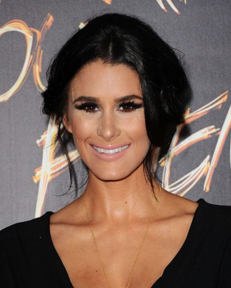 Brittany Furlan in a black dress poses for a picture.